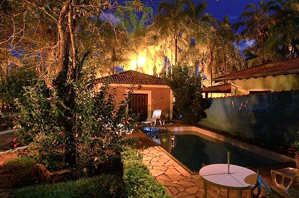 Piscina iluminada à noite em meio ao jardim